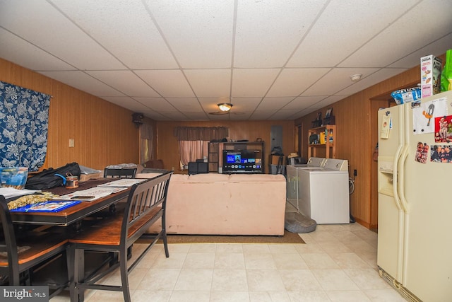 dining space with washer and dryer, a paneled ceiling, and wooden walls