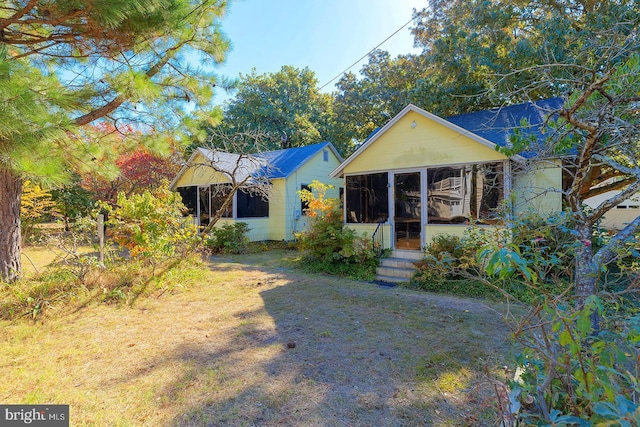 view of front of house featuring a sunroom and a front lawn