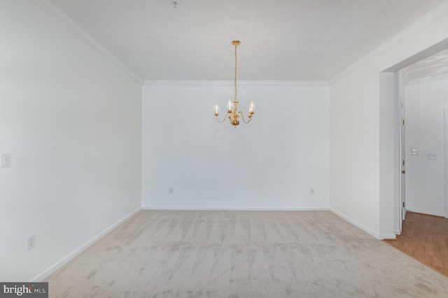 spare room featuring light colored carpet, ornamental molding, and a chandelier