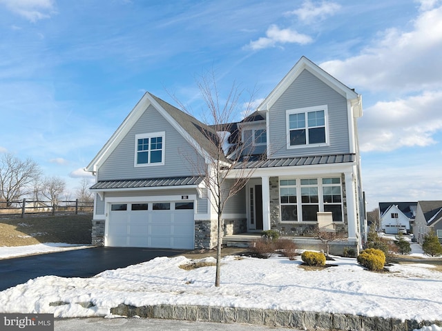 view of front facade featuring a porch, an attached garage, driveway, stone siding, and a standing seam roof