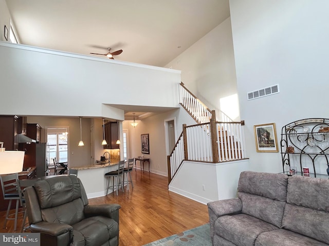 living room with wood-type flooring, a towering ceiling, and ceiling fan