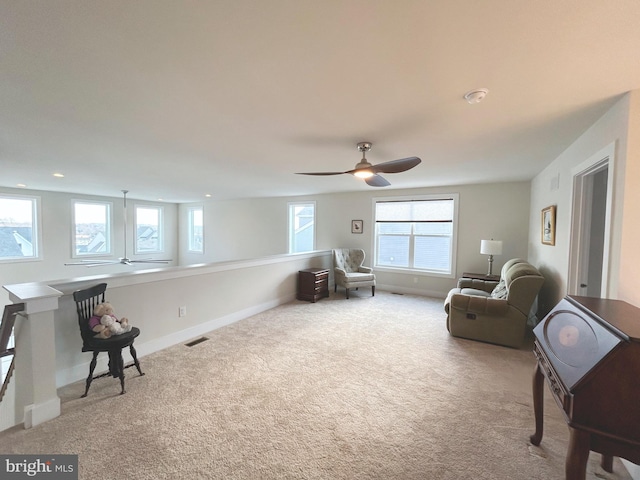 living area featuring light carpet and ceiling fan