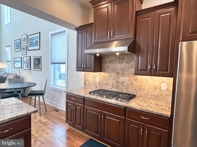 kitchen featuring dark brown cabinetry, backsplash, and stainless steel appliances