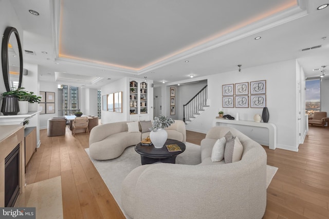 living room featuring a raised ceiling and light hardwood / wood-style flooring