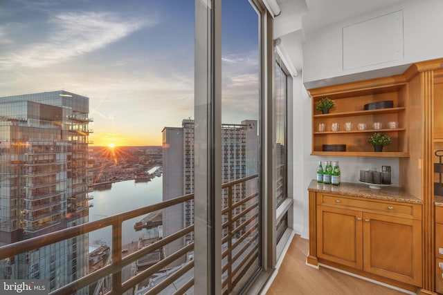 balcony at dusk featuring a water view