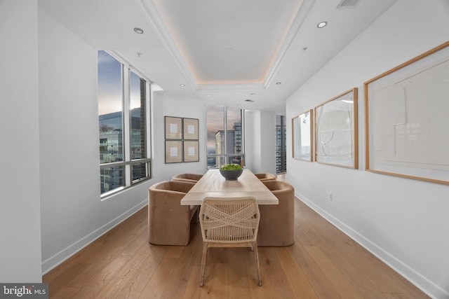 dining space featuring a tray ceiling, light hardwood / wood-style flooring, and a wealth of natural light