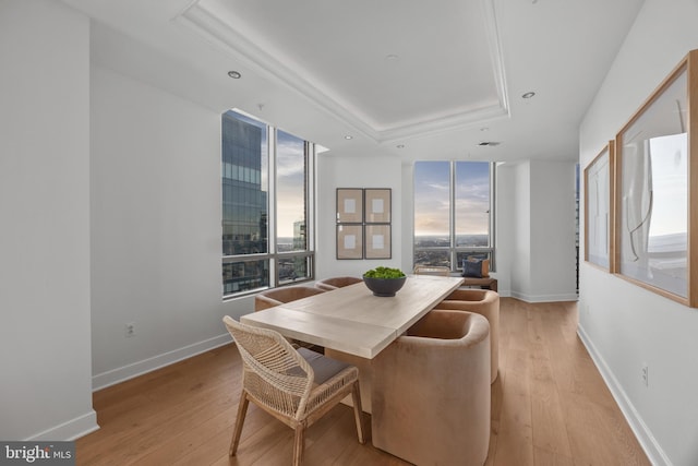 dining area featuring a raised ceiling and light wood-type flooring