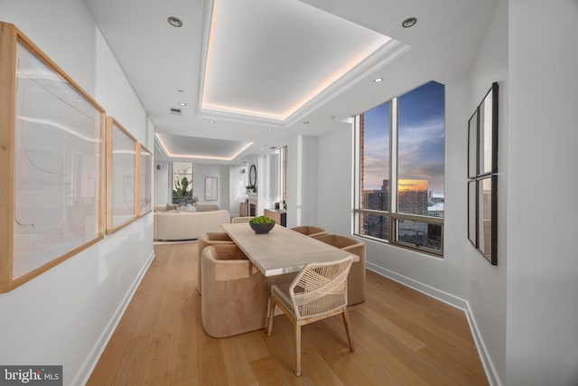 dining space featuring a raised ceiling and light hardwood / wood-style floors