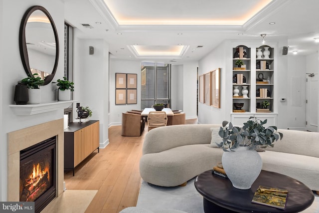 living room featuring a tray ceiling and light hardwood / wood-style floors