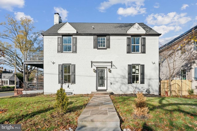 colonial-style house featuring a front lawn