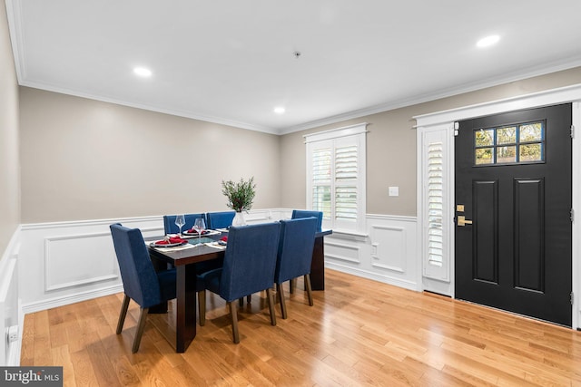 dining room with ornamental molding and light hardwood / wood-style flooring