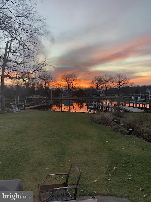 yard at dusk featuring a water view