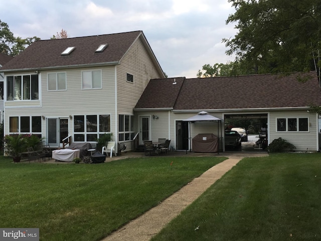 back of house with roof with shingles, a lawn, and a patio