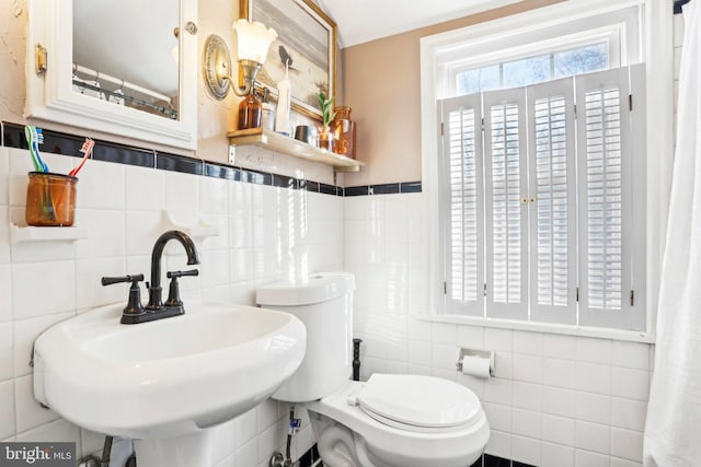 bathroom featuring tile walls, sink, and toilet