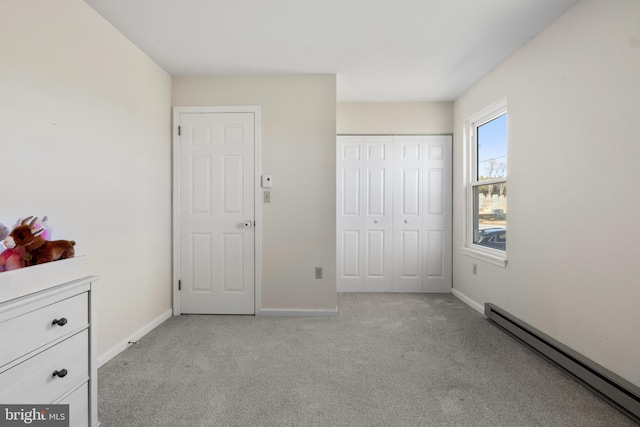 unfurnished bedroom featuring baseboard heating, a closet, and light colored carpet