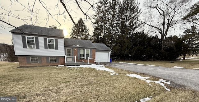 tri-level home featuring a garage and a lawn