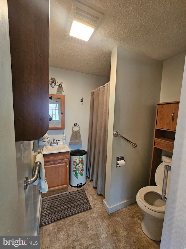 full bathroom featuring a textured ceiling, curtained shower, toilet, vanity, and baseboards