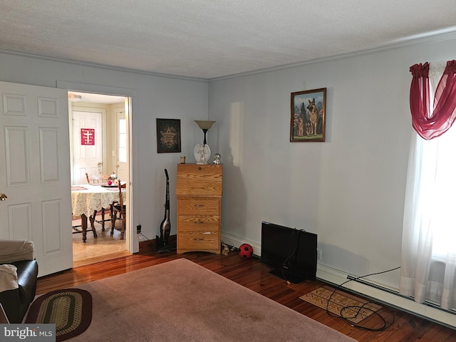 bedroom with a textured ceiling, a baseboard heating unit, and wood finished floors