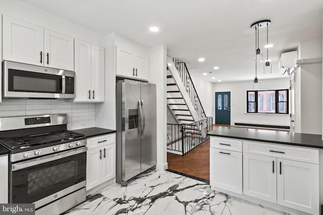 kitchen featuring tasteful backsplash, a wall mounted air conditioner, hanging light fixtures, stainless steel appliances, and white cabinets