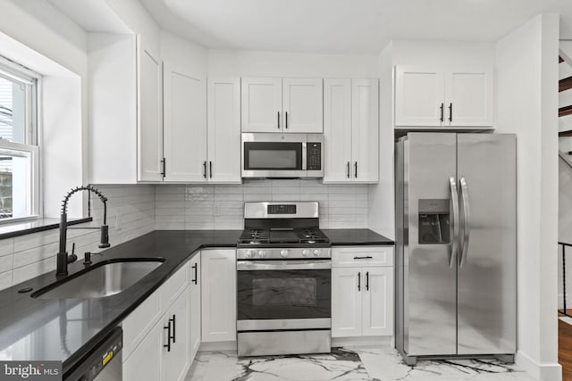 kitchen with stainless steel appliances, white cabinetry, sink, and decorative backsplash