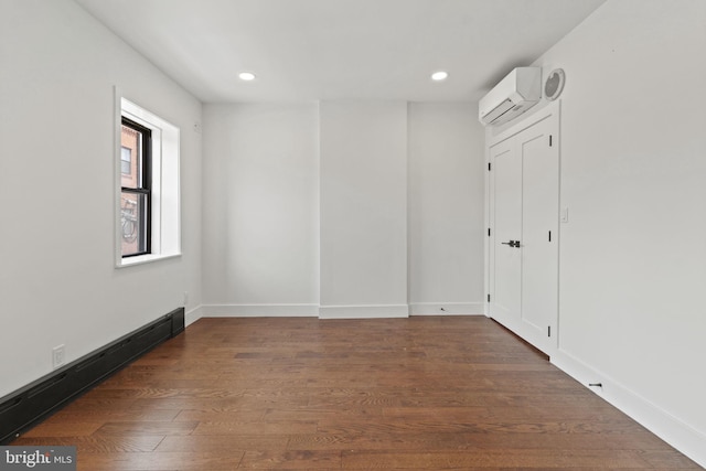 unfurnished room with baseboard heating, dark hardwood / wood-style flooring, and a wall mounted AC