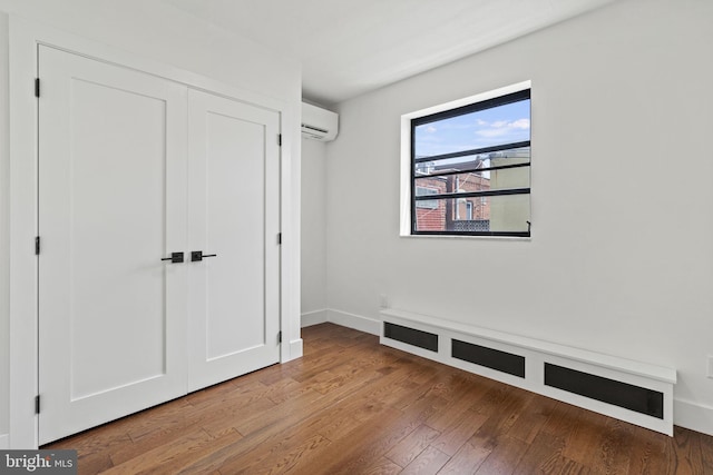 interior space with wood-type flooring, a wall mounted AC, and a closet