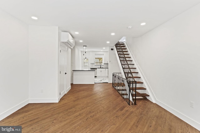 unfurnished living room featuring hardwood / wood-style floors and an AC wall unit