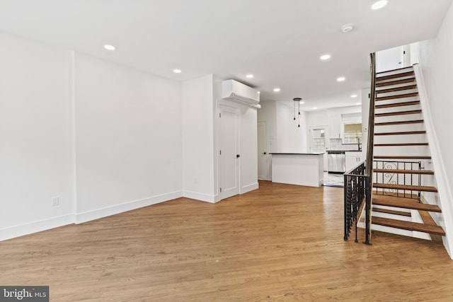 unfurnished living room featuring a wall unit AC and light hardwood / wood-style flooring