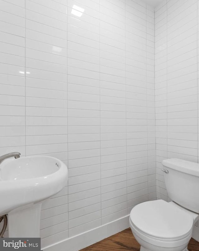 bathroom with tile walls, sink, wood-type flooring, and toilet