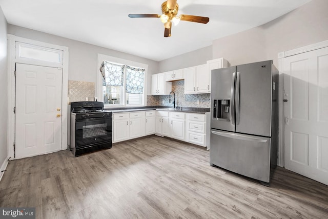 kitchen featuring stainless steel fridge, black gas range, tasteful backsplash, light hardwood / wood-style floors, and white cabinets