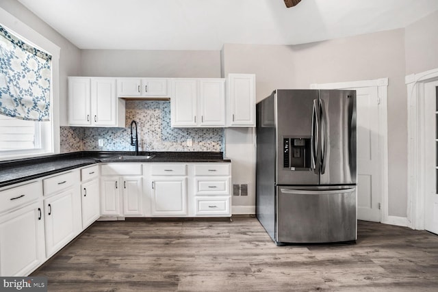 kitchen featuring sink, hardwood / wood-style flooring, white cabinetry, stainless steel fridge with ice dispenser, and decorative backsplash