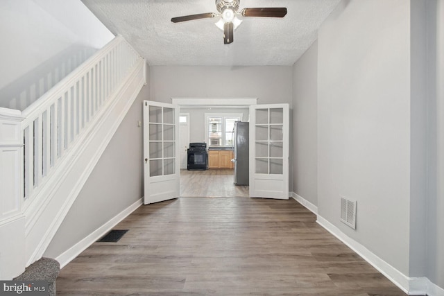 interior space with hardwood / wood-style floors, a textured ceiling, and french doors