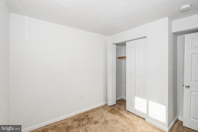 unfurnished bedroom with light colored carpet and a closet