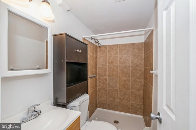 bathroom with vanity, tiled shower, and toilet