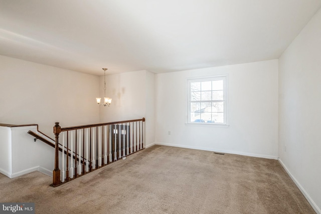 carpeted empty room with a notable chandelier