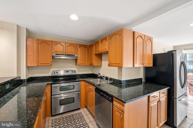 kitchen featuring dark stone countertops, sink, light tile patterned floors, and stainless steel appliances