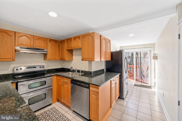 kitchen with appliances with stainless steel finishes, sink, dark stone countertops, and light tile patterned floors