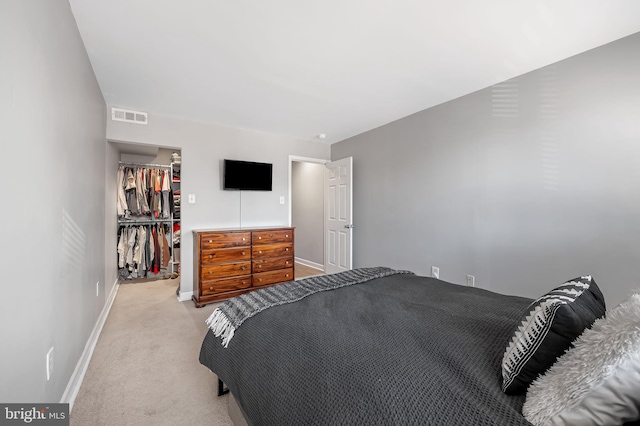 carpeted bedroom featuring a walk in closet and a closet