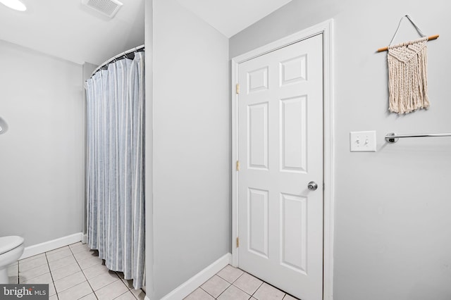 bathroom featuring a shower with shower curtain, toilet, and tile patterned flooring