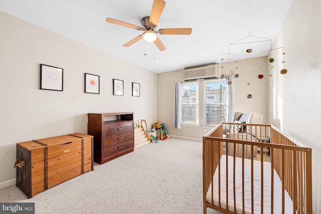 carpeted bedroom with ceiling fan, a wall mounted AC, and a crib