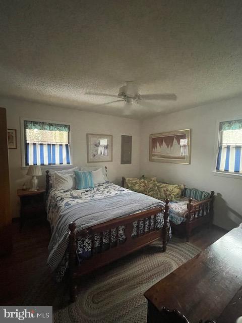 bedroom featuring ceiling fan, dark hardwood / wood-style floors, and a textured ceiling