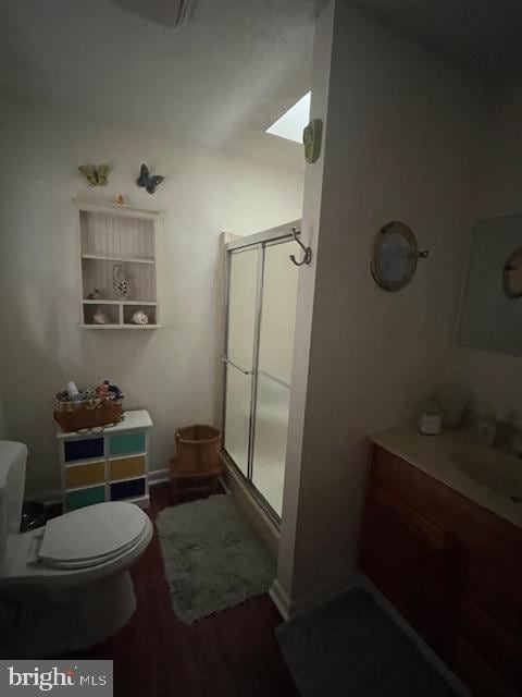 bathroom featuring wood-type flooring, sink, toilet, and a shower with shower door