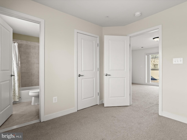 unfurnished bedroom with light colored carpet and ensuite bathroom