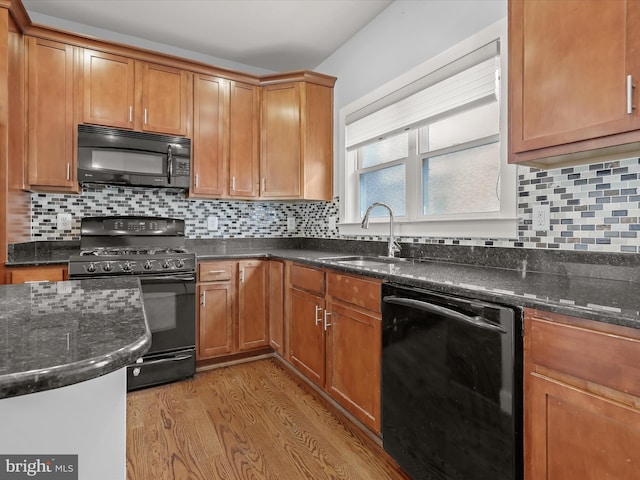 kitchen with light wood-type flooring, sink, decorative backsplash, and black appliances