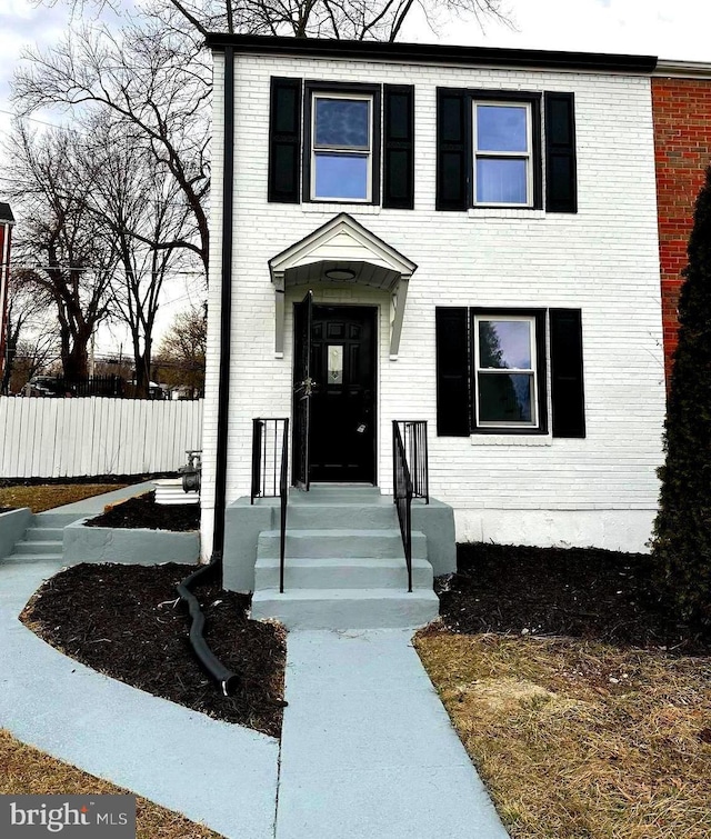 view of front facade with brick siding and fence