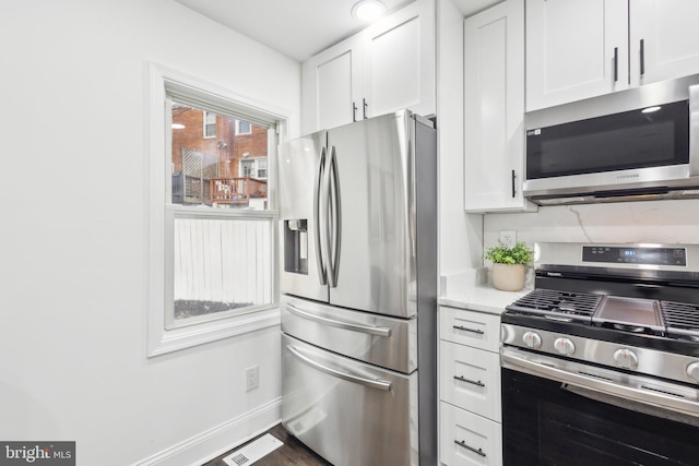 kitchen with stainless steel appliances, visible vents, baseboards, white cabinets, and light stone countertops