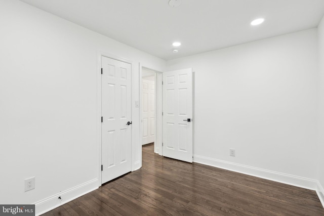 spare room featuring recessed lighting, dark wood finished floors, and baseboards