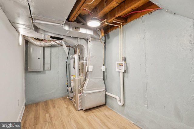 unfinished below grade area featuring electric panel, heating unit, and wood finished floors