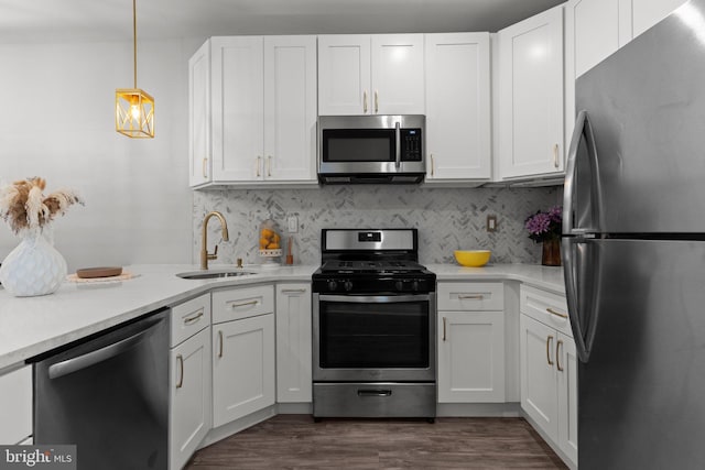 kitchen with hanging light fixtures, stainless steel appliances, sink, and white cabinets