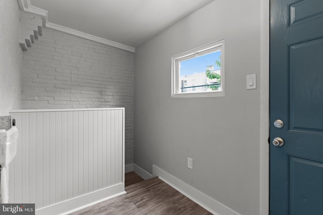 laundry room featuring hardwood / wood-style floors and brick wall